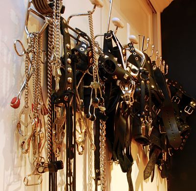 hanging wall rack filled with bdsm chrome leather punishing devices